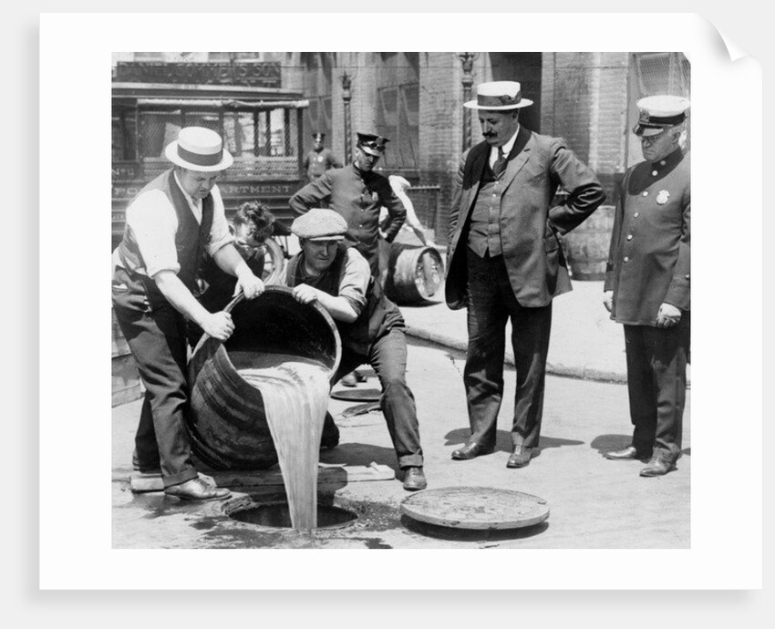 New York City Deputy Police Commissioner John A. Leach, watching agents pour liquor into sewer following a raid during the height of prohibition, c.1921 by American Photographer