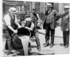 New York City Deputy Police Commissioner John A. Leach, watching agents pour liquor into sewer following a raid during the height of prohibition, c.1921 by American Photographer