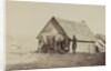 A group of soldiers, and two young men, one an African American, stand outside of log cabin quarters by American Photographer