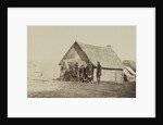 A group of soldiers, and two young men, one an African American, stand outside of log cabin quarters by American Photographer