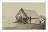 A group of soldiers, and two young men, one an African American, stand outside of log cabin quarters by American Photographer