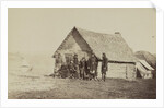 A group of soldiers, and two young men, one an African American, stand outside of log cabin quarters by American Photographer
