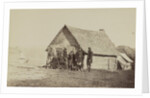 A group of soldiers, and two young men, one an African American, stand outside of log cabin quarters by American Photographer