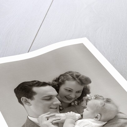 1940s Father Cradling Baby Daughter Feeding Her Bottle With Mother Looking Over His Shoulder by Anonymous
