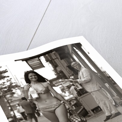 1970s Man Ogling Sexy Young Woman Walking Down City Street Wearing Only A Bikini by Anonymous