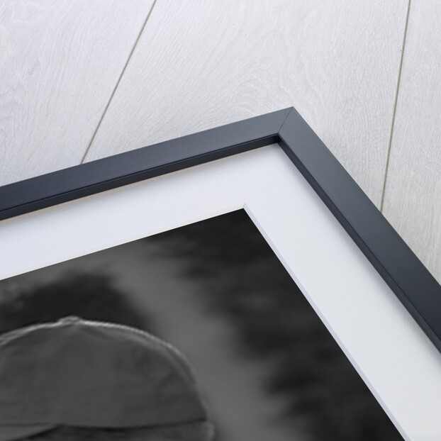 1950s Side View Of Boy In Baseball Cap and Striped T-Shirt Blowing Up Swirled Balloon by Anonymous