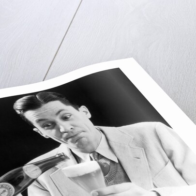 1930s Man Pouring Beer From Bottle Into Glass Look Of Anticipation Wearing Suit Tie Sweater by Anonymous