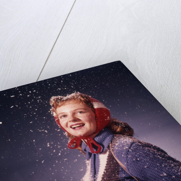 1960s Young Woman Wearing Red Mittens Ear Muffs Blue Sweater Holding Ice Skates In Falling Snow by Anonymous