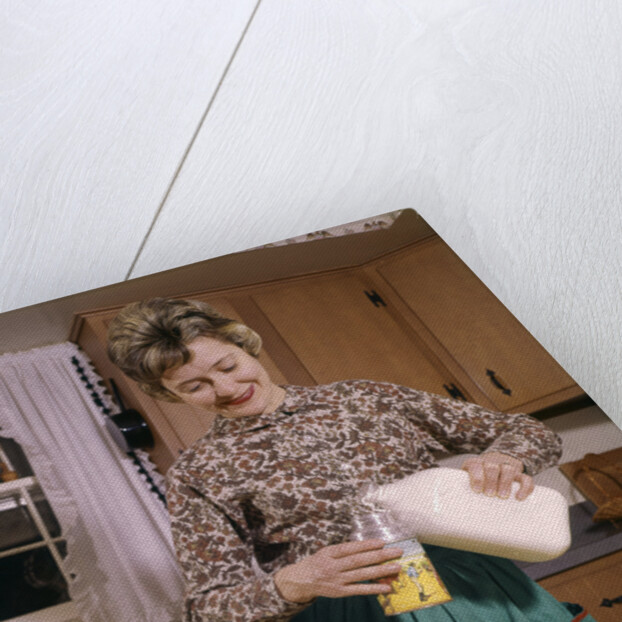 1960s Woman Housewife Mother Wearing Apron In Kitchen Pouring Milk Into Thermos For School Lunch by Anonymous