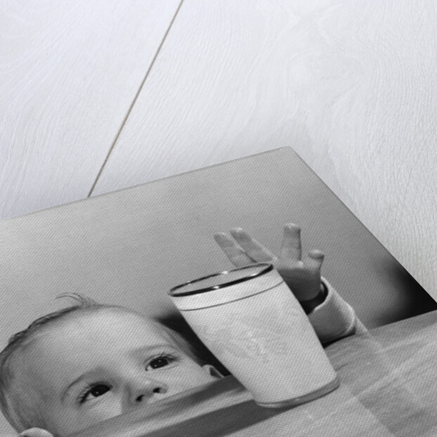 1950s Toddler Reaching Up To Table To Grab Milk Glass by Anonymous