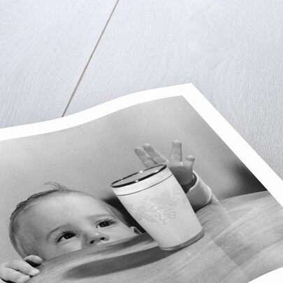 1950s Toddler Reaching Up To Table To Grab Milk Glass by Anonymous