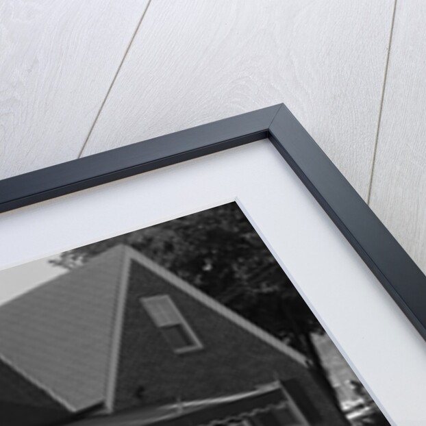 1950s Family Standing By White Fence Looking At Brick House by Anonymous