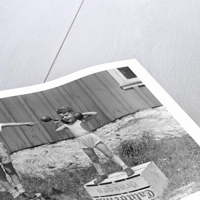 1930s 1940s Boys Playing Carnival Strongman One Lifting Dumbbells Other Announcing Act Through Megaphone by Anonymous