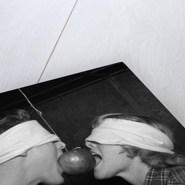 1950s Blindfolded Couple Trying To Eat An Apple Hanging In Air From A String Inside by Anonymous