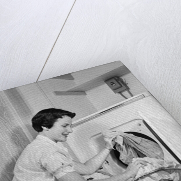 1950s Woman Kneeling Removing Clothes Laundry From Automatic Dryer by Anonymous
