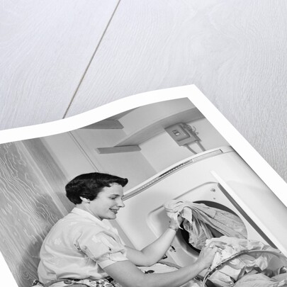 1950s Woman Kneeling Removing Clothes Laundry From Automatic Dryer by Anonymous