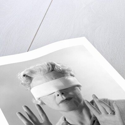 1960s Elderly Woman Wearing Blindfold Holding Up Her Hands by Anonymous