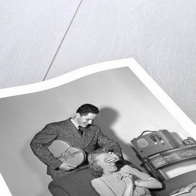 1940s Teen Couple Boy With Hand Over Girl Eyes Surprising Her With Box Of Valentines Day Candy by Anonymous