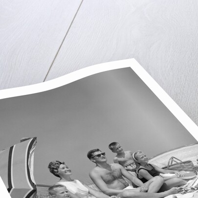 1960s Family Portrait Mother Father Daughter And Two Sons Sitting On Beach Under Umbrella by Anonymous