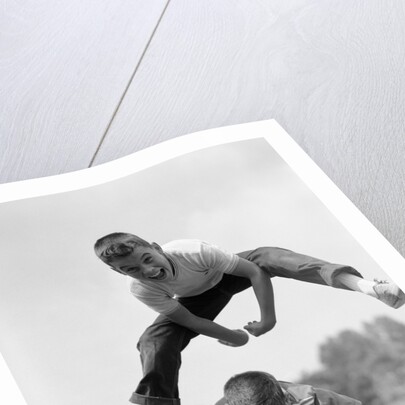 1960s Retro Boys Playing Leap Frog Outside Sky Grass Jump Jumping Crouching by Anonymous