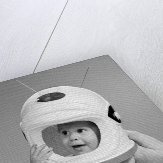1960s Baby In Diaper Seated Holding Astronaut Helmet With Antennae On Head by Anonymous