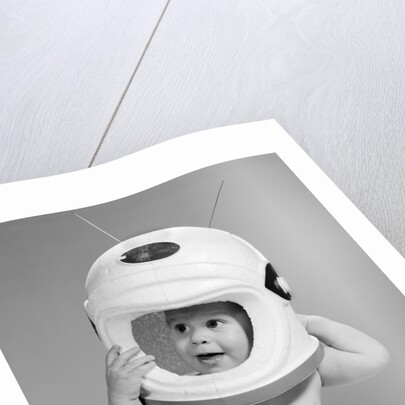 1960s Baby In Diaper Seated Holding Astronaut Helmet With Antennae On Head by Anonymous