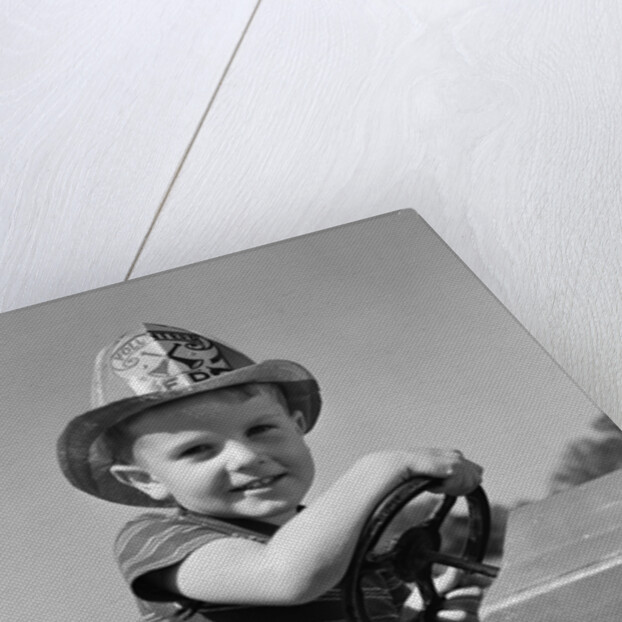1940s Boy Playing Fireman In Toy Fire Truck Wearing Fireman's Safety Hat Holding Steering Wheel by Anonymous