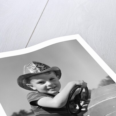 1940s Boy Playing Fireman In Toy Fire Truck Wearing Fireman's Safety Hat Holding Steering Wheel by Anonymous