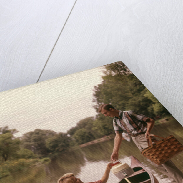 1960s Young Couple Loading Picnic Basket Thermos Into Canoe by Anonymous