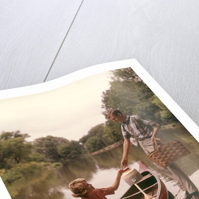 1960s Young Couple Loading Picnic Basket Thermos Into Canoe by Anonymous
