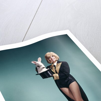 1960s Young Woman In Stage Magician Coat And Short Shorts Pulling Rabbit Out Of Top Hat by Anonymous
