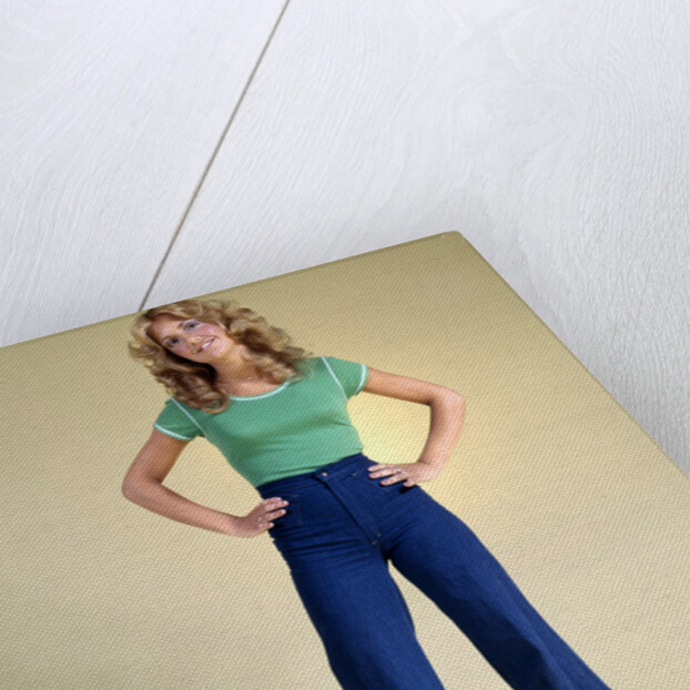 1970s Young Woman With Long Curly Hair Standing Hands On Hips In Bell Bottom Denim Blue Jeans by Anonymous