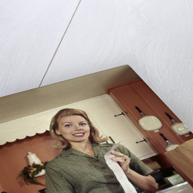 1960s Young Housewife While Checking Grocery Shopping Receipt In Kitchen by Anonymous