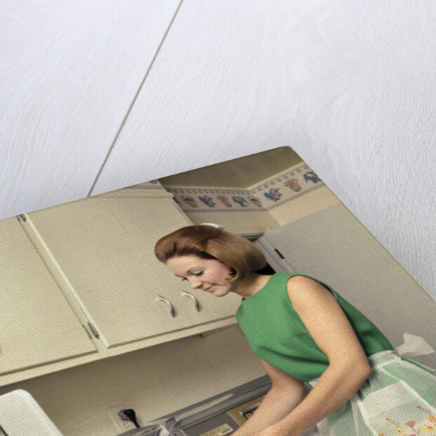 1970s Woman Housewife Homemaker Wearing Apron Loading Laundry Into Washing Machine by Anonymous