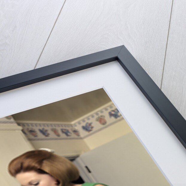 1970s Woman Housewife Homemaker Wearing Apron Loading Laundry Into Washing Machine by Anonymous