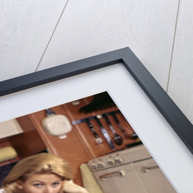 1960s Weary Dejected Woman Housewife Homemaker Sitting On Full Laundry Basket In Kitchen by Anonymous
