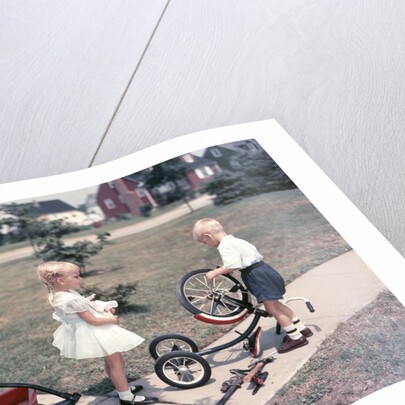 1950s Little Girl Sister Holding Doll Watching Little Boy Brother Repair Tricycle by Anonymous