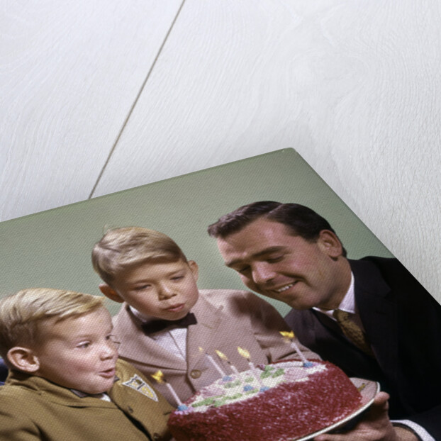 1960s Mother And Father Holding Birthday Cake And Sons Blowing Out Candles by Anonymous