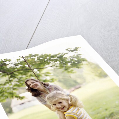1970s Woman Mother With Girl Daughter Swinging Playing On Rope Swing by Anonymous