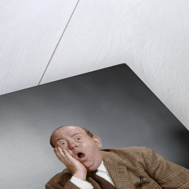 1960s Shocked Balding Executive With Hand To Cheek Sitting At Desk by Anonymous
