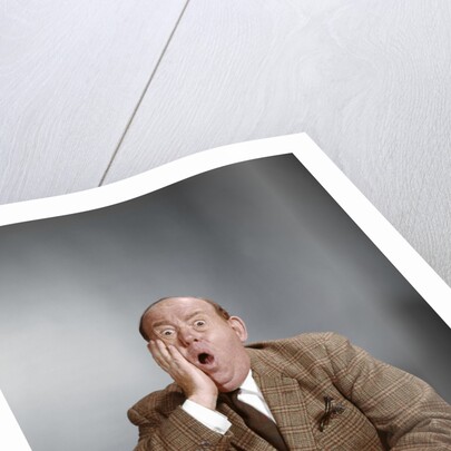 1960s Shocked Balding Executive With Hand To Cheek Sitting At Desk by Anonymous