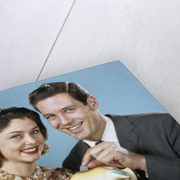 1950s 1960s Young Couple Man And Woman Put Quarter In Savings Piggy Bank by Anonymous