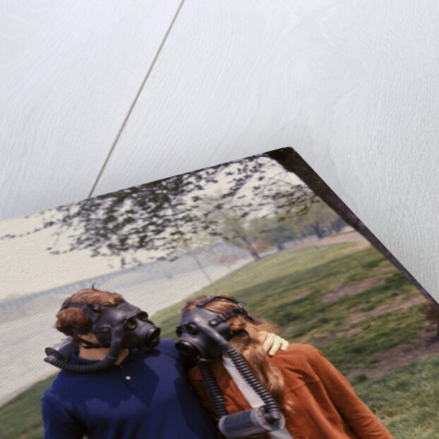 1970s Young Romantic Teenage Couple Man Woman Wearing Gas Masks Walking By River by Anonymous