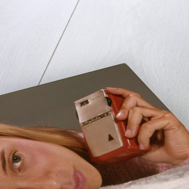 1950s 1960s Teenage Girl Holding Red Silver Small Transistor Radio To Her Ear Listening by Anonymous