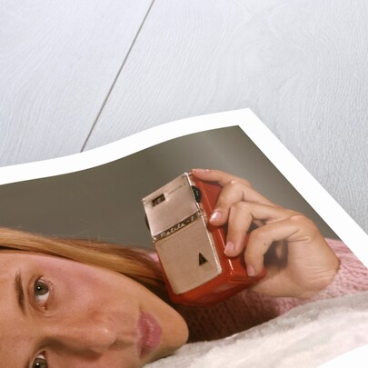 1950s 1960s Teenage Girl Holding Red Silver Small Transistor Radio To Her Ear Listening by Anonymous