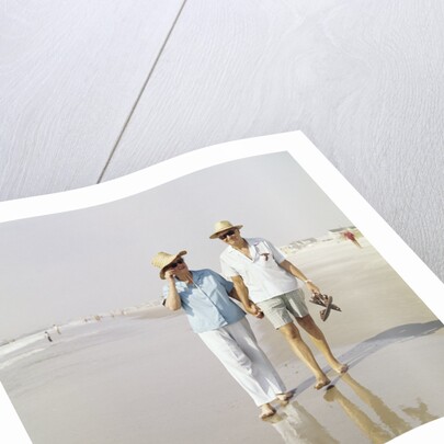 1970s Senior Couple Walking Beach Holding Hands Wearing Straw Hats by Anonymous