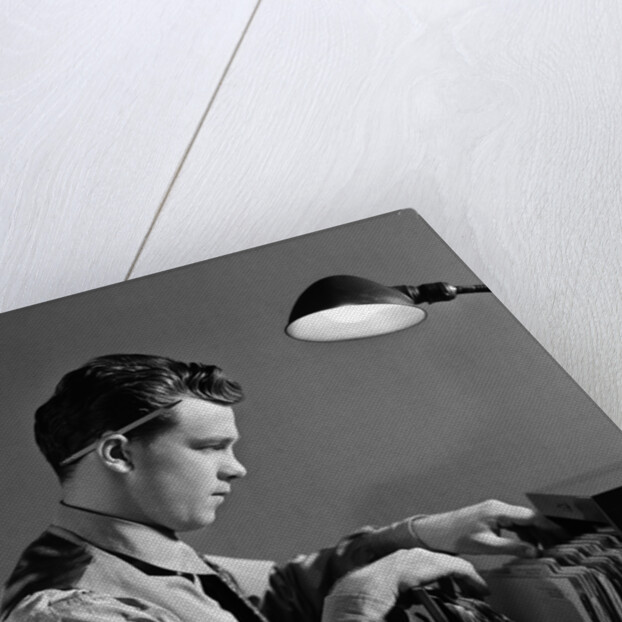 1940s Young Man Office File Clerk Putting Records Into Filing Cabinet Drawer by Anonymous