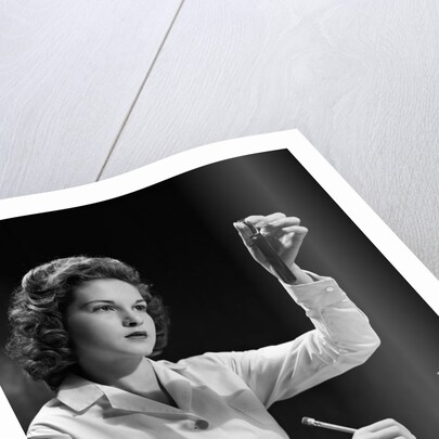 1940s Student Nurse Holding Up Test Tube While Taking Notes In Science Class by Anonymous