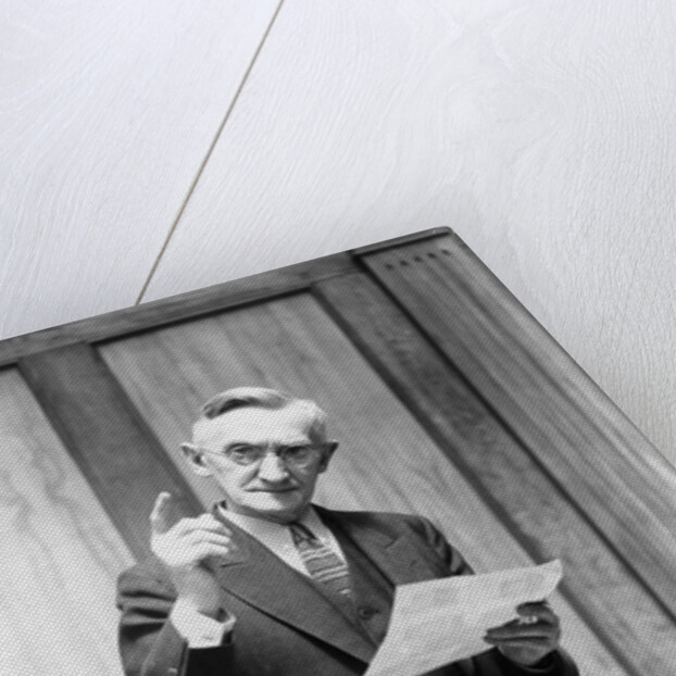 1930s Elderly Man In Office Standing Behind Desk Gesturing With Raised Finger by Anonymous