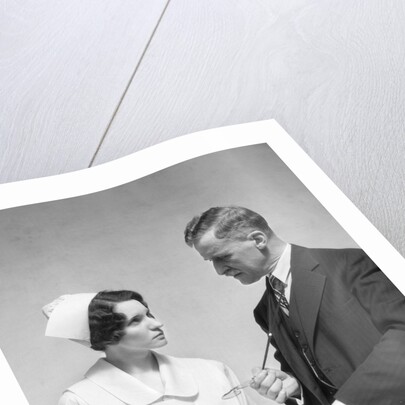 1930s Doctor In Suit And Necktie Confers With Nurse In Uniform And Cap Holding Clipboard Chart by Corbis